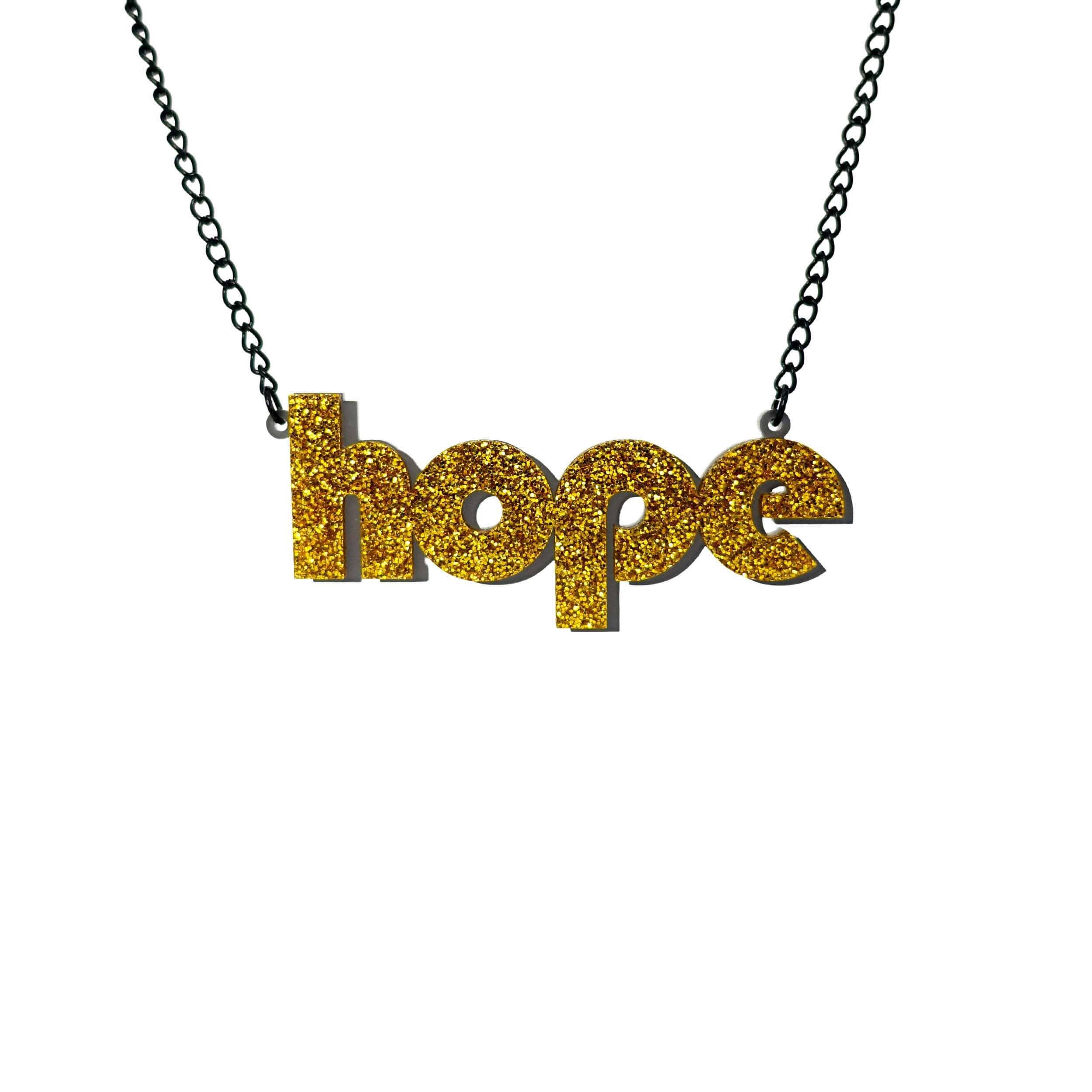 Hope statement necklace in ultra gold glitter with backing layer that works as a drop shadow, shown hanging against a white background.