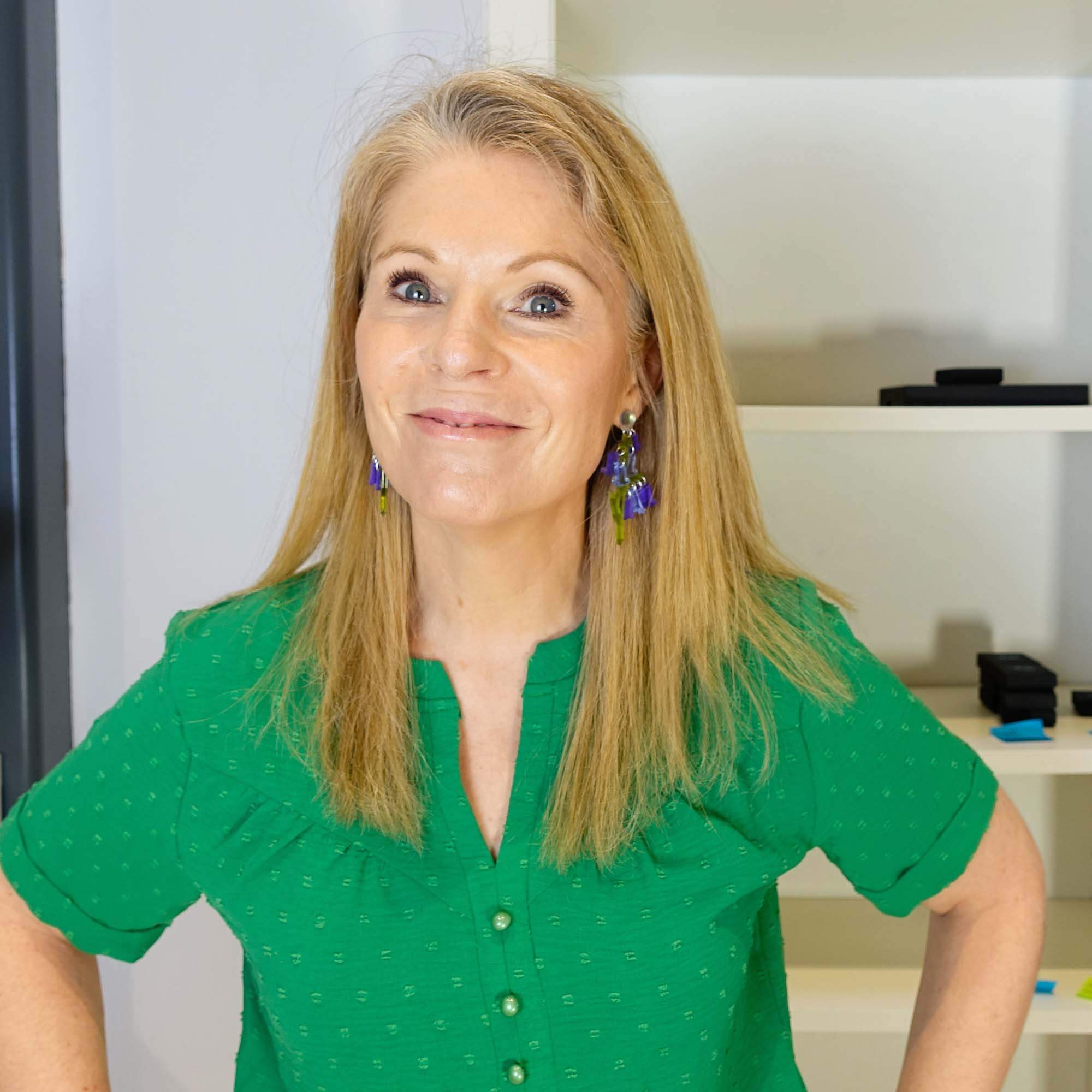 Sarah Day smiles wearing Bluebell earrings in her studio.