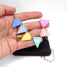 C*nting Bunting necklace in pastel colours shown held in my hand above a Wear & Resist gift box. 