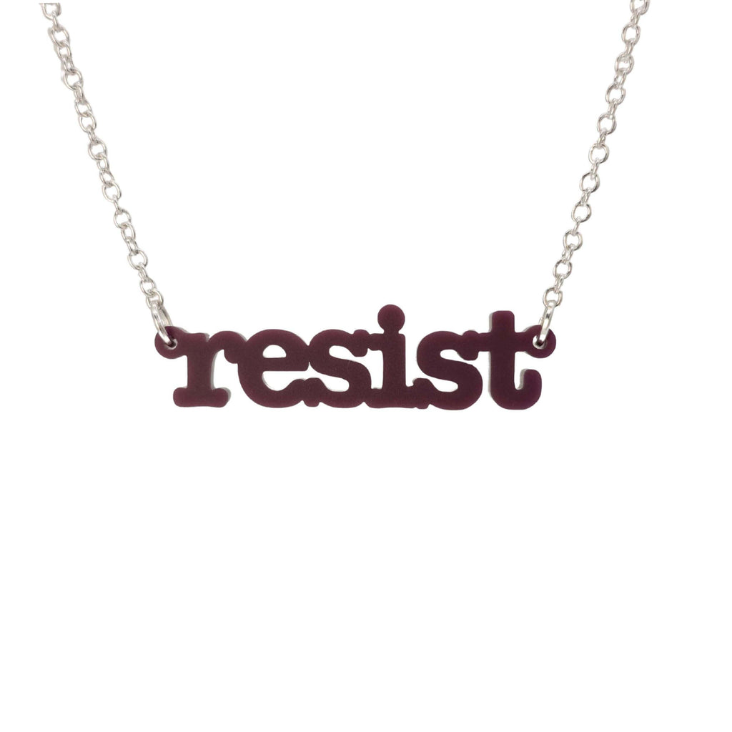 Cassis Resist necklace in typewriter font hanging on a silver chain against a white background. 