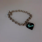 Stainless steel charm bracelet with slate Be Brave heart charm glowing.  