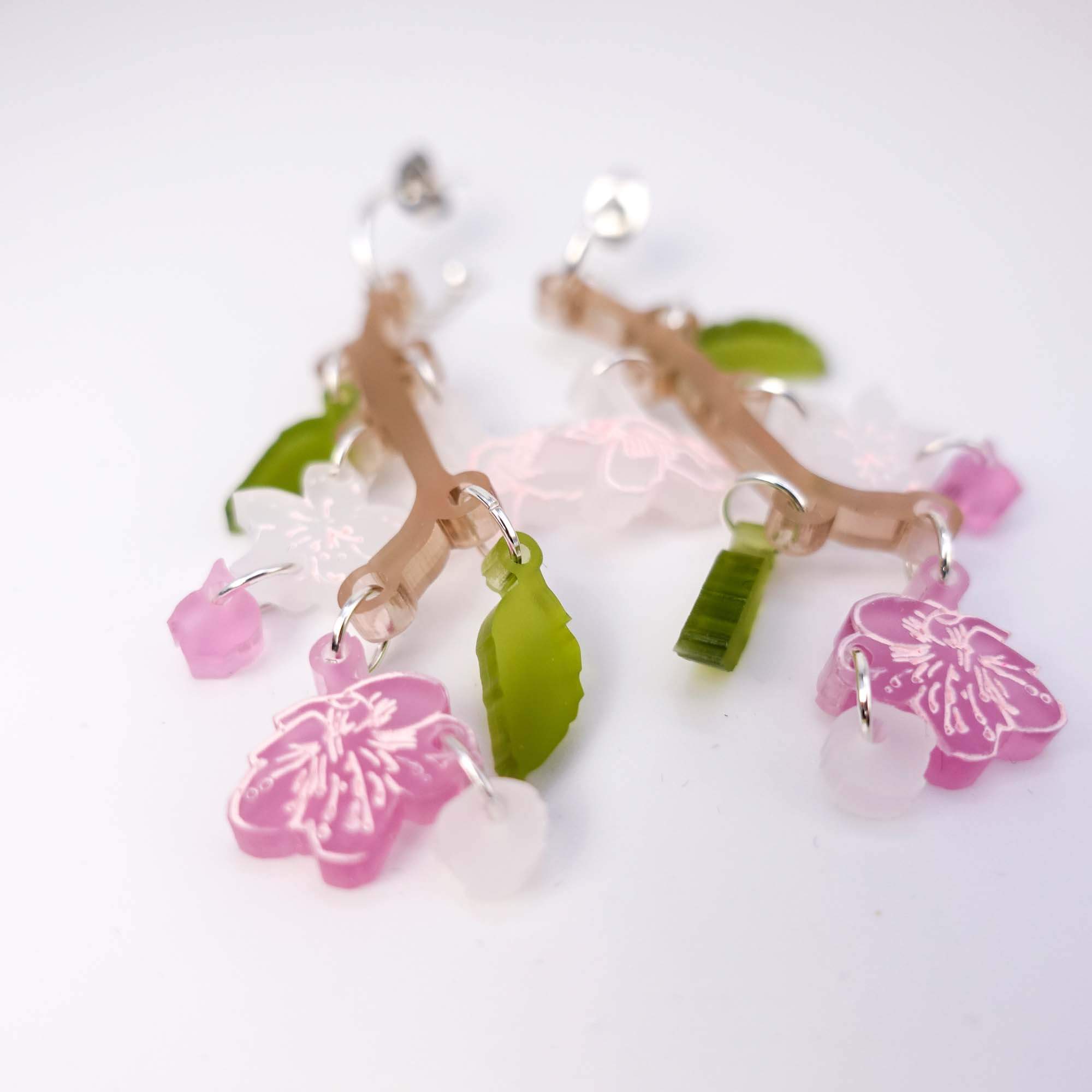 Cherry blossom hoop earrings shown up close laying on a white surface. 