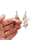 Cherry blossom hoop earrings shown hanging against a white background with my hand behind for scale. 