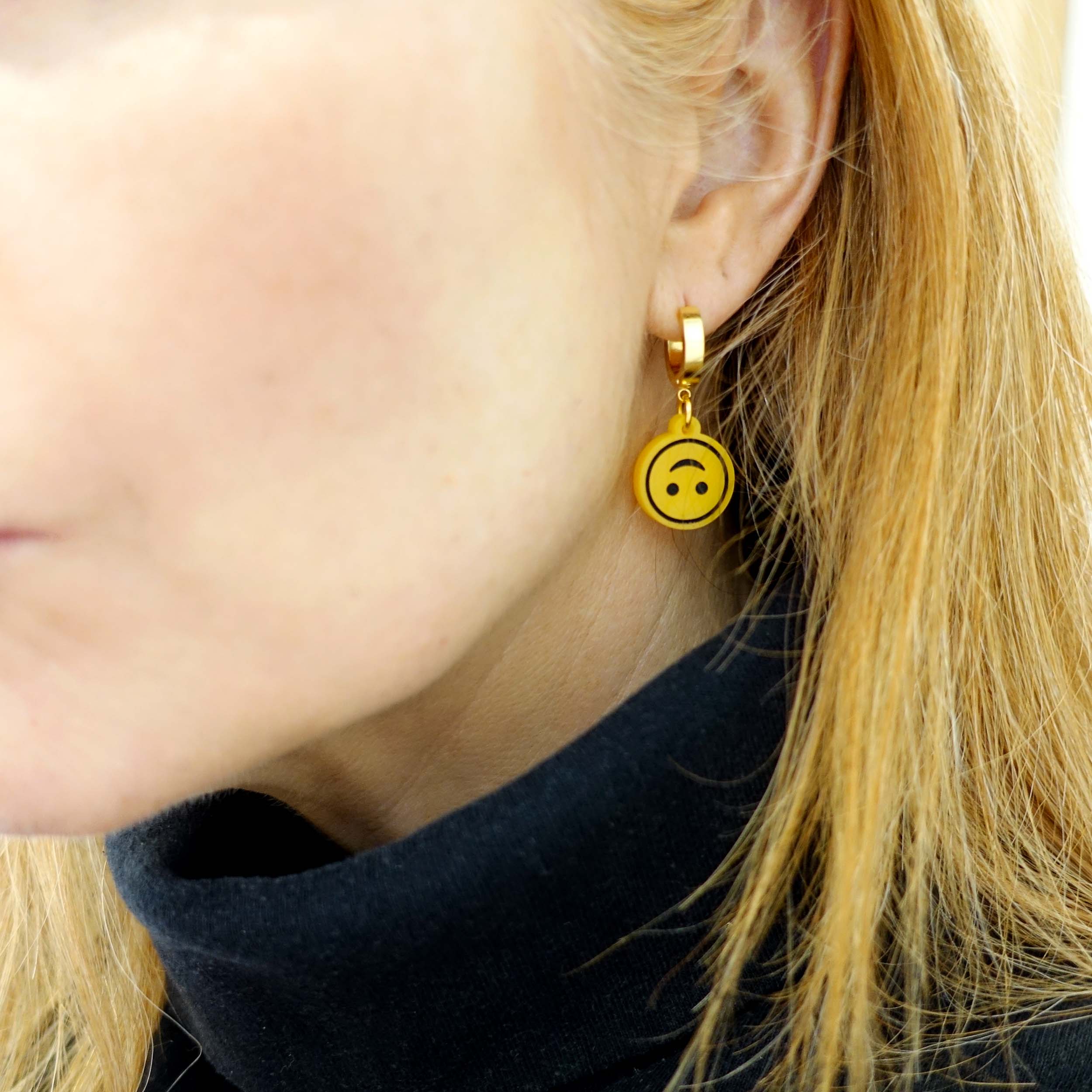 Sarah Day wears Upside-down smiley face earrings on gold huggie hoops.  