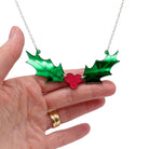 Holly necklace shown hanging against a white background with my hand for scale and to show the light on the mirror acrylic. 