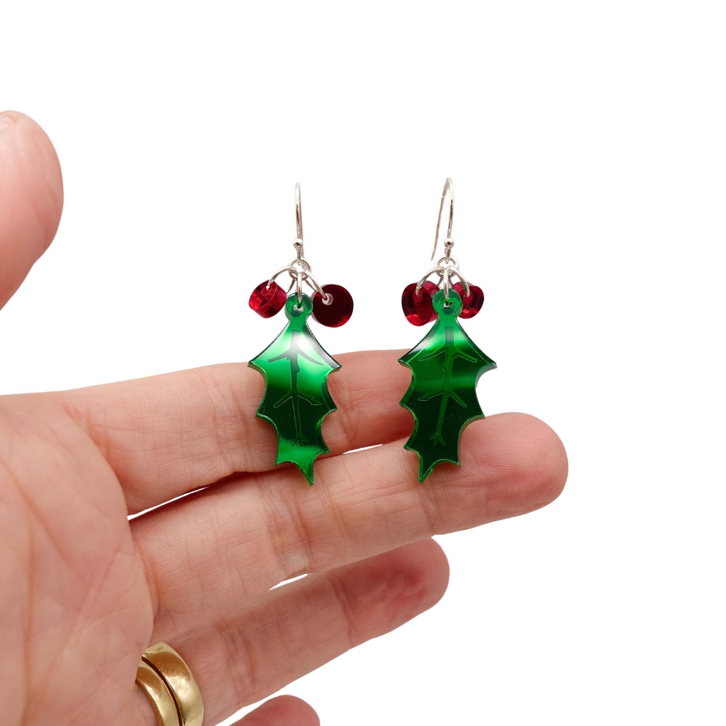 Delicate Holly earrings shown hanging against a white background with my hand for scale. 