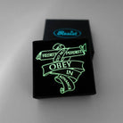 Do Not Obey in Advance, Resist, Persist pin shown glowing in the dark in a small Wear and Resist gift box. 