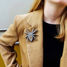 Eliza wears the All Hail Lady Hail Spider brooch on a tan corduroy jacket. 