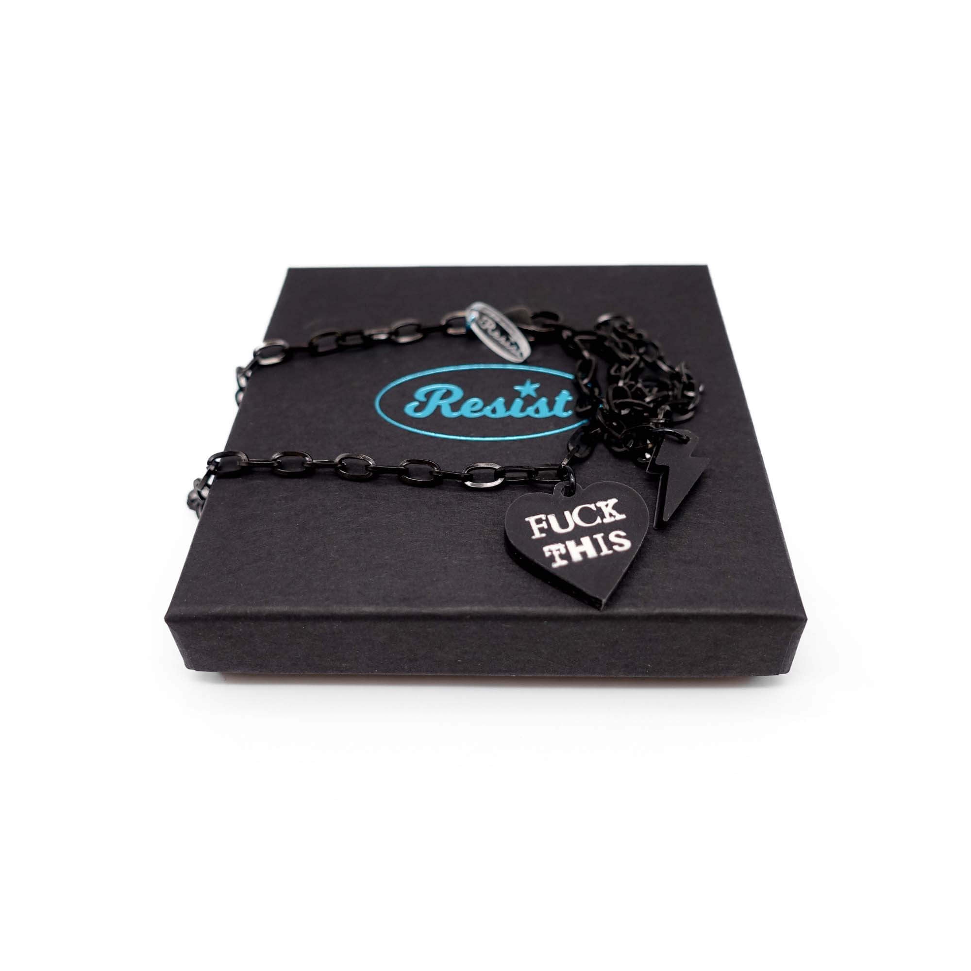 F*ck This punk necklace in slate frost with matching lightning bolt on a black stainless steel chain, shown on a Wear and Resist gift box. 