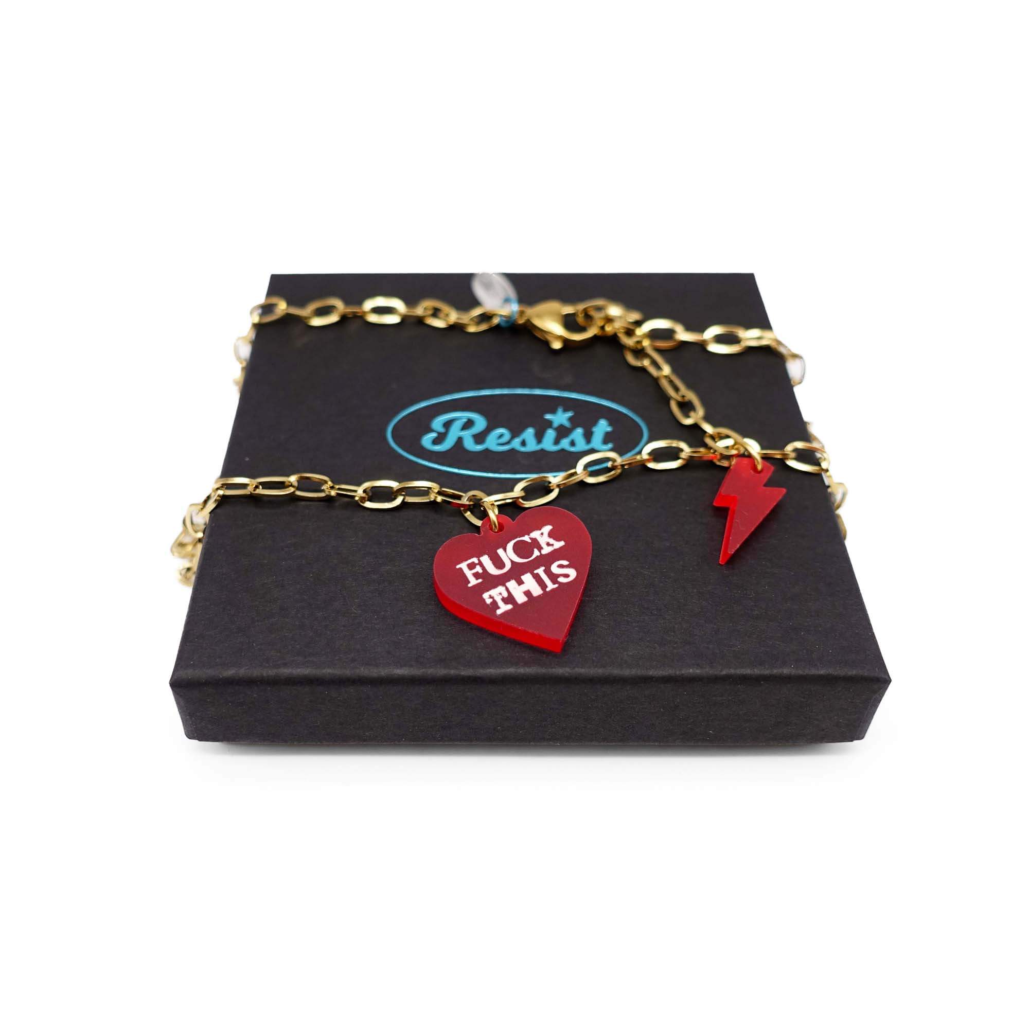 F*ck This punk necklace in chilli red with matching lightning bolt on a gold stainless steel chain, shown on a Wear and Resist gift box. 