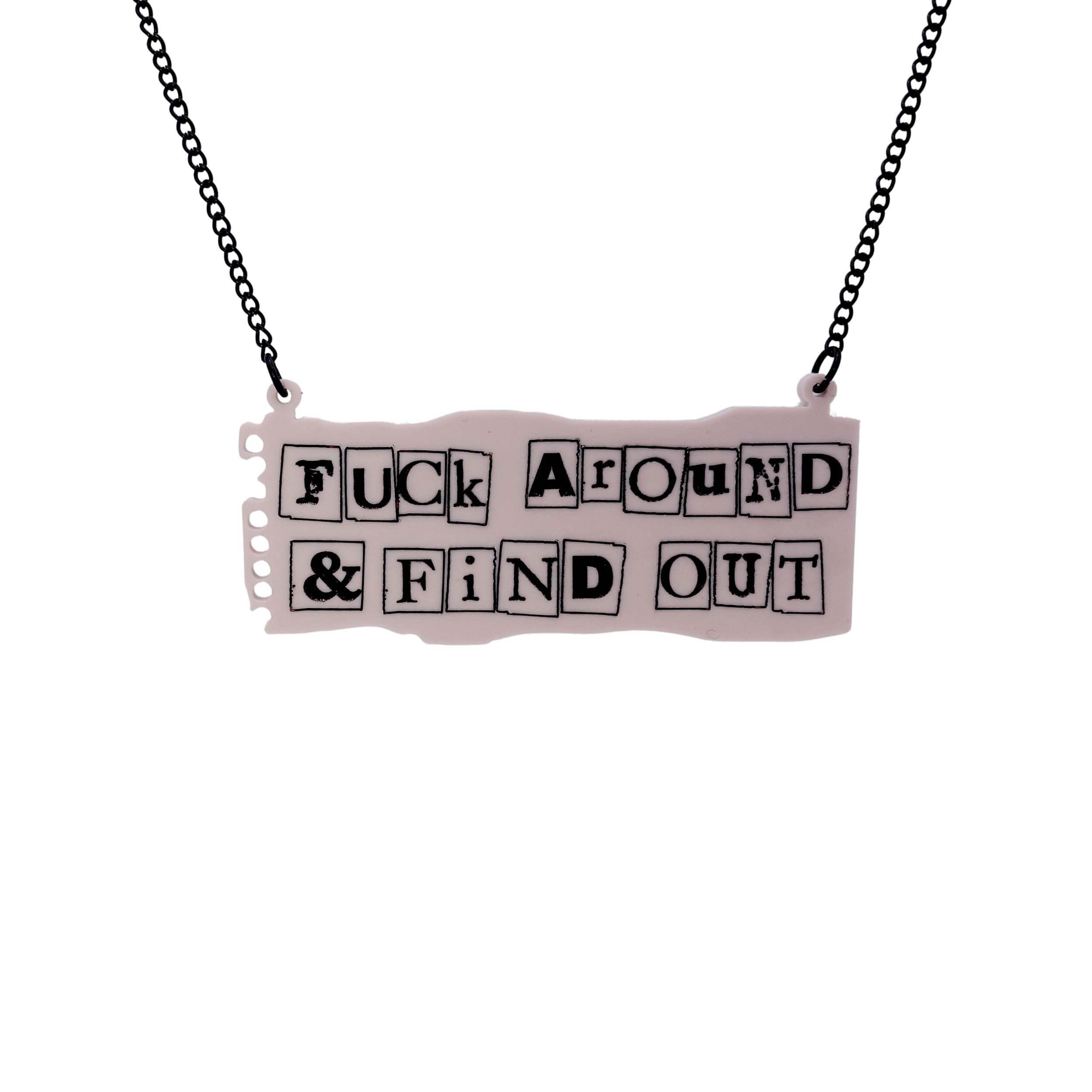 F*ck Around and Find Out necklace in the style of a ransom note on pale pink notepaper, shown hanging on a black chain adjustable to three lengths. 