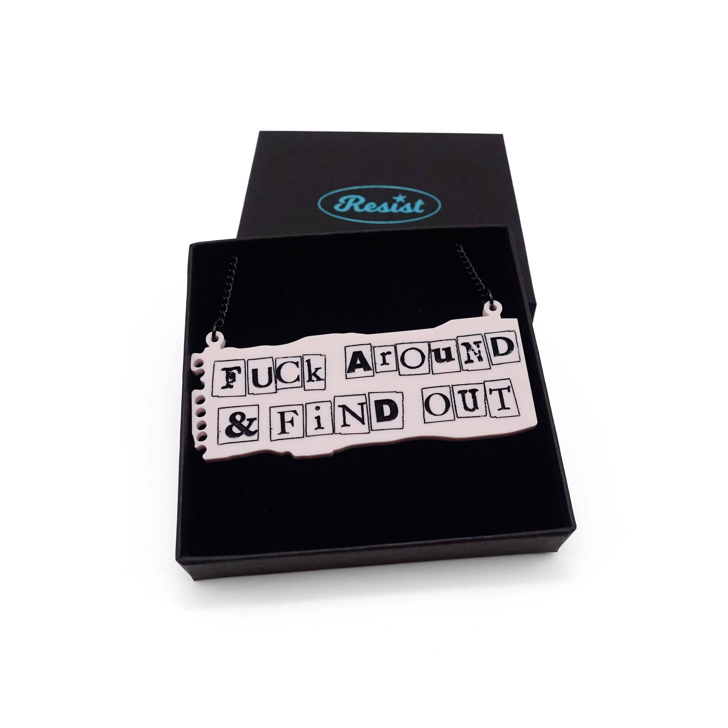 F*ck Around and Find Out necklace in the style of a ransom note on pale pink notepaper, shown in a Wear and Resist gift box.