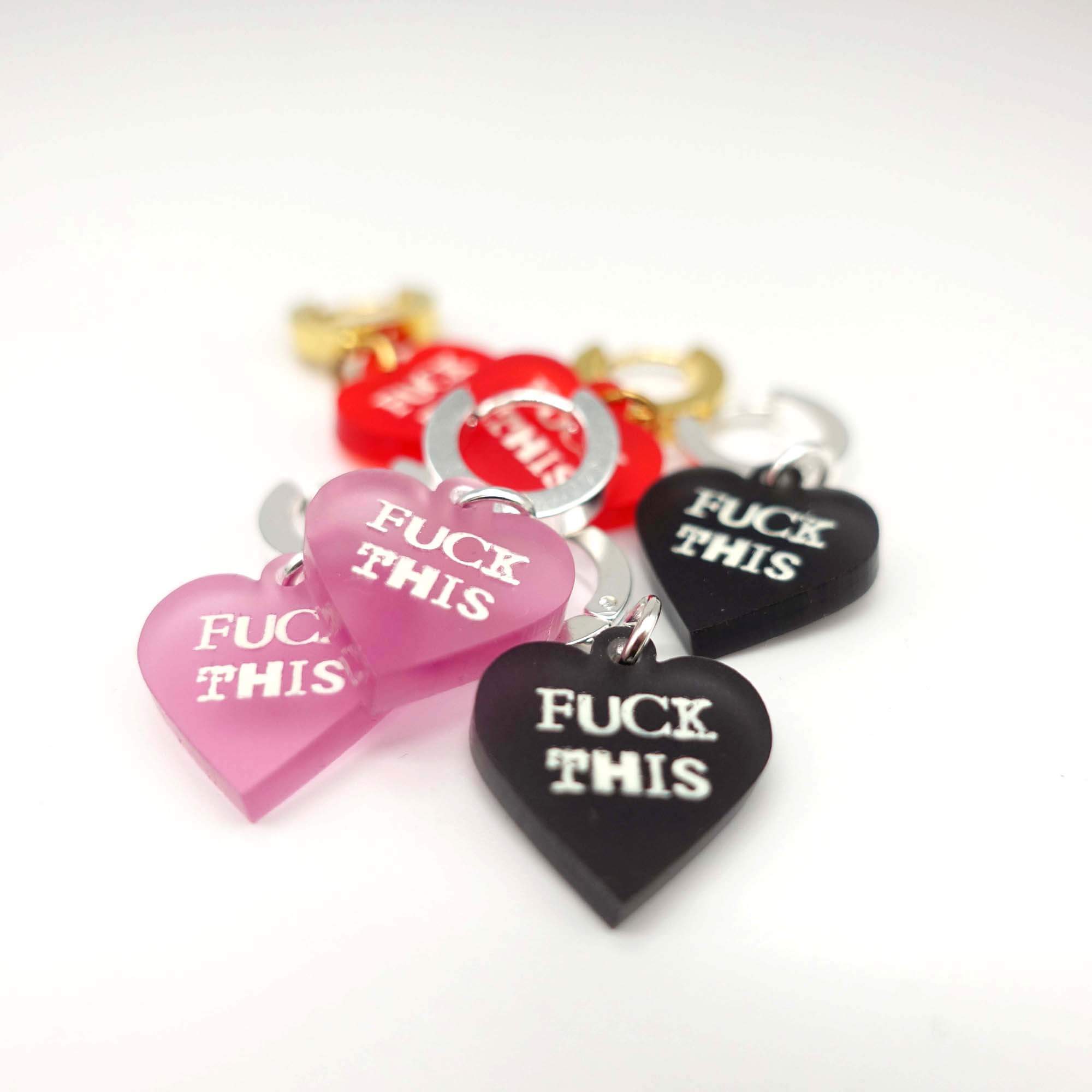 F*ck This huggie hoop earrings in pale pink, chilli red and slate frost etched with glow-in-the-dark pigment. 