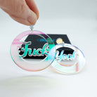 F*ck Yeah earrings in iridescent acrylic. Shown with a hand holding one for scale. 