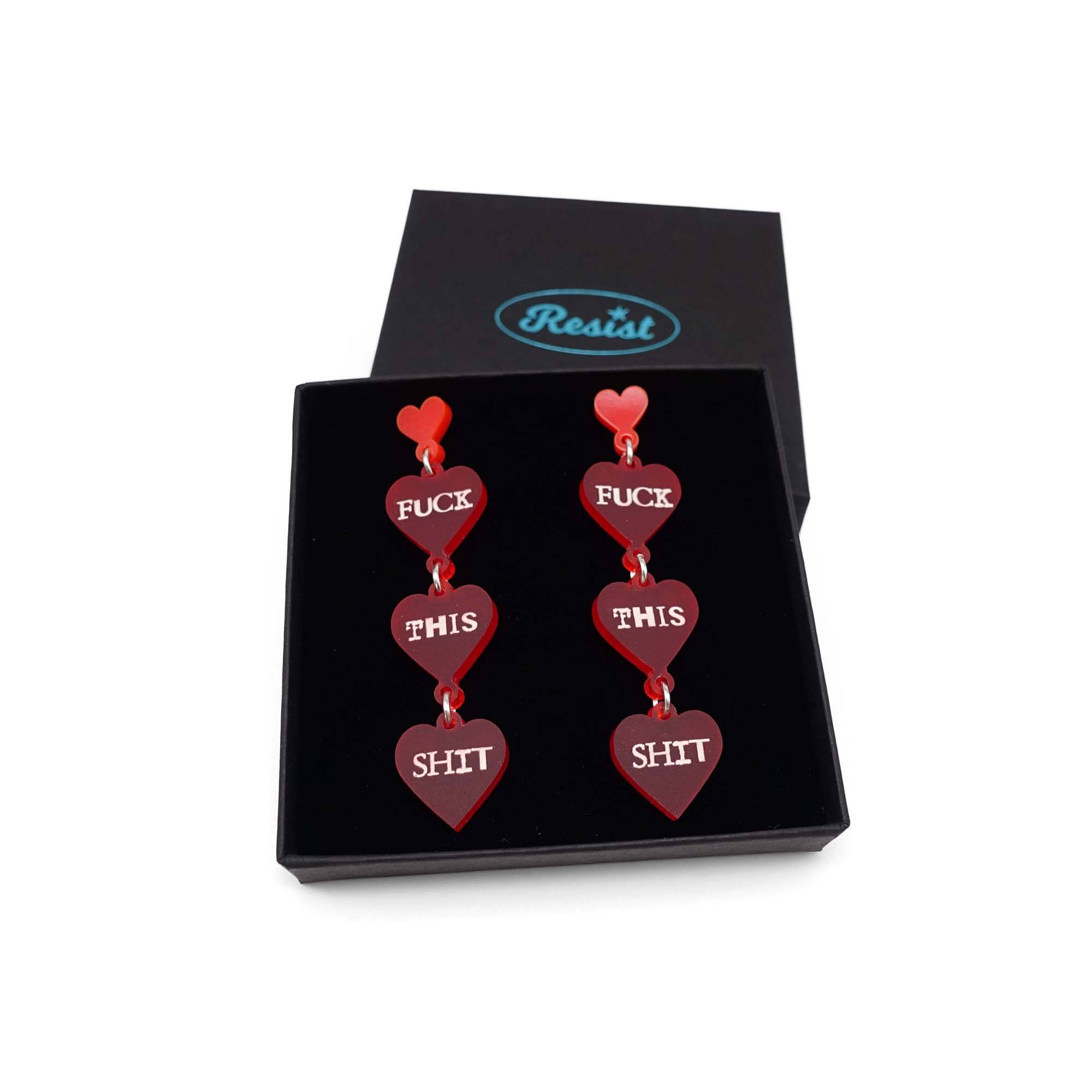 F*ck this Sh*t earrings in chilli red with glow-in-the-dark words shown in a Wear and Resist gift box. 