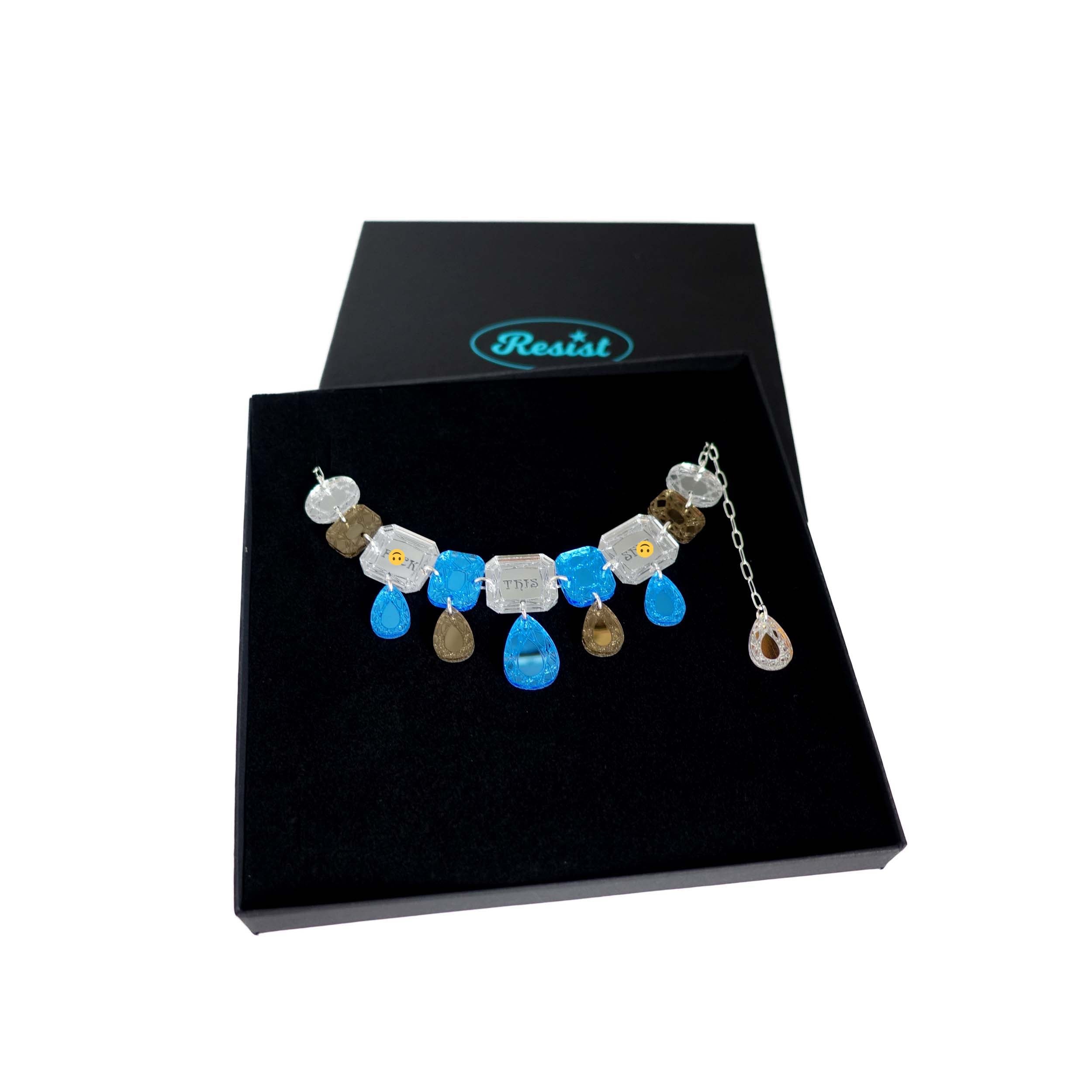 A blue silver and bronze F*ck this Sh*t jewel necklace, shown in a Wear and Resist gift box. 