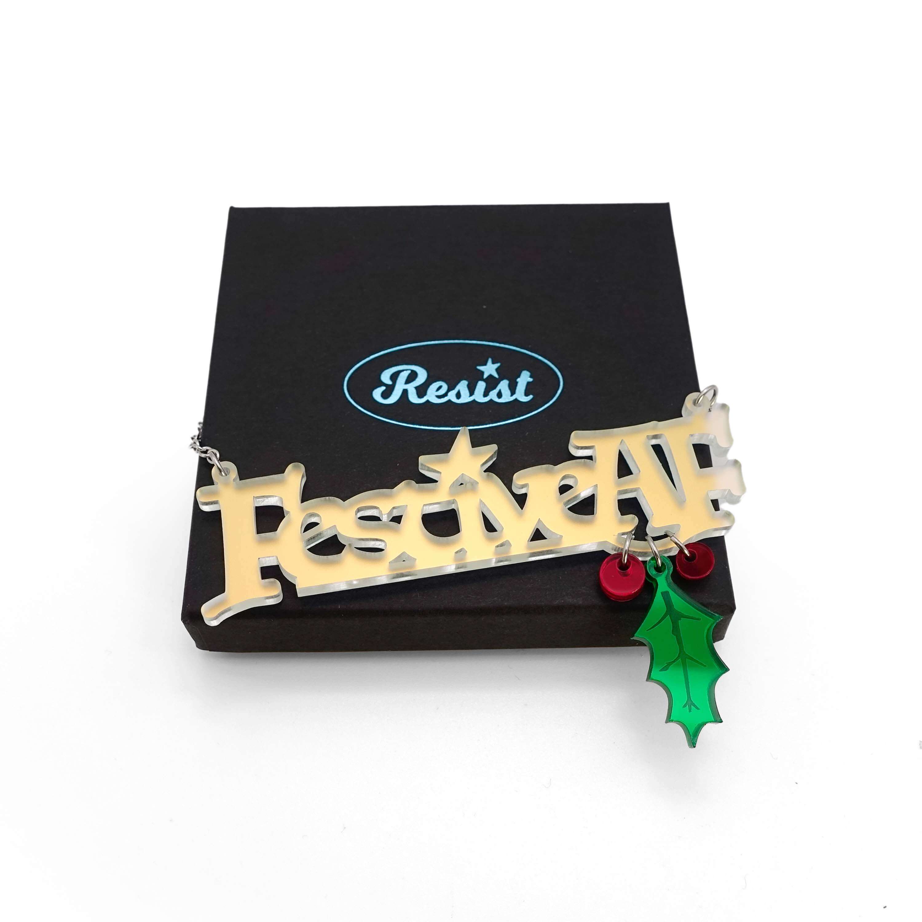 Festive AF matte iridescent necklace with hanging holly leaf and berries, shown on top of a Wear and Resist box.
