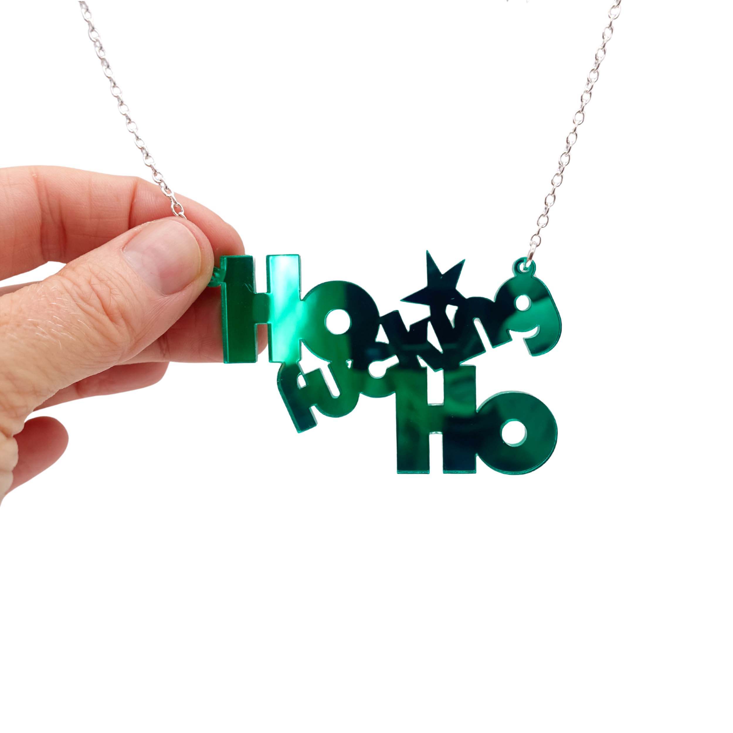 Ho F*cking Ho necklace in electric green, shown hanging against a white background with my hand holding it for size, and to show the reflective quality of the mirror acrylic. 