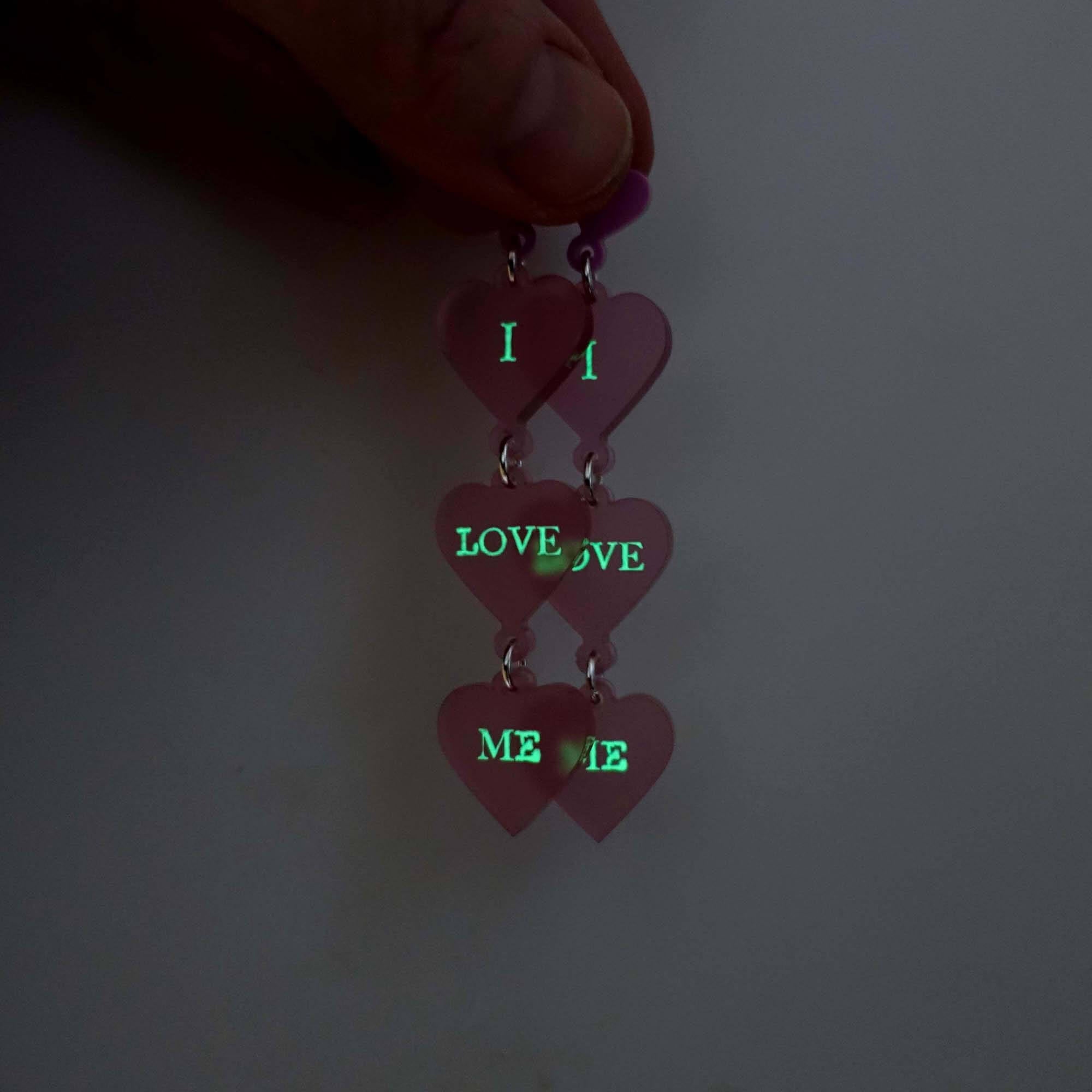 I Love Me heart drop earrings in pale pink frost with shown glowing in the dark. 