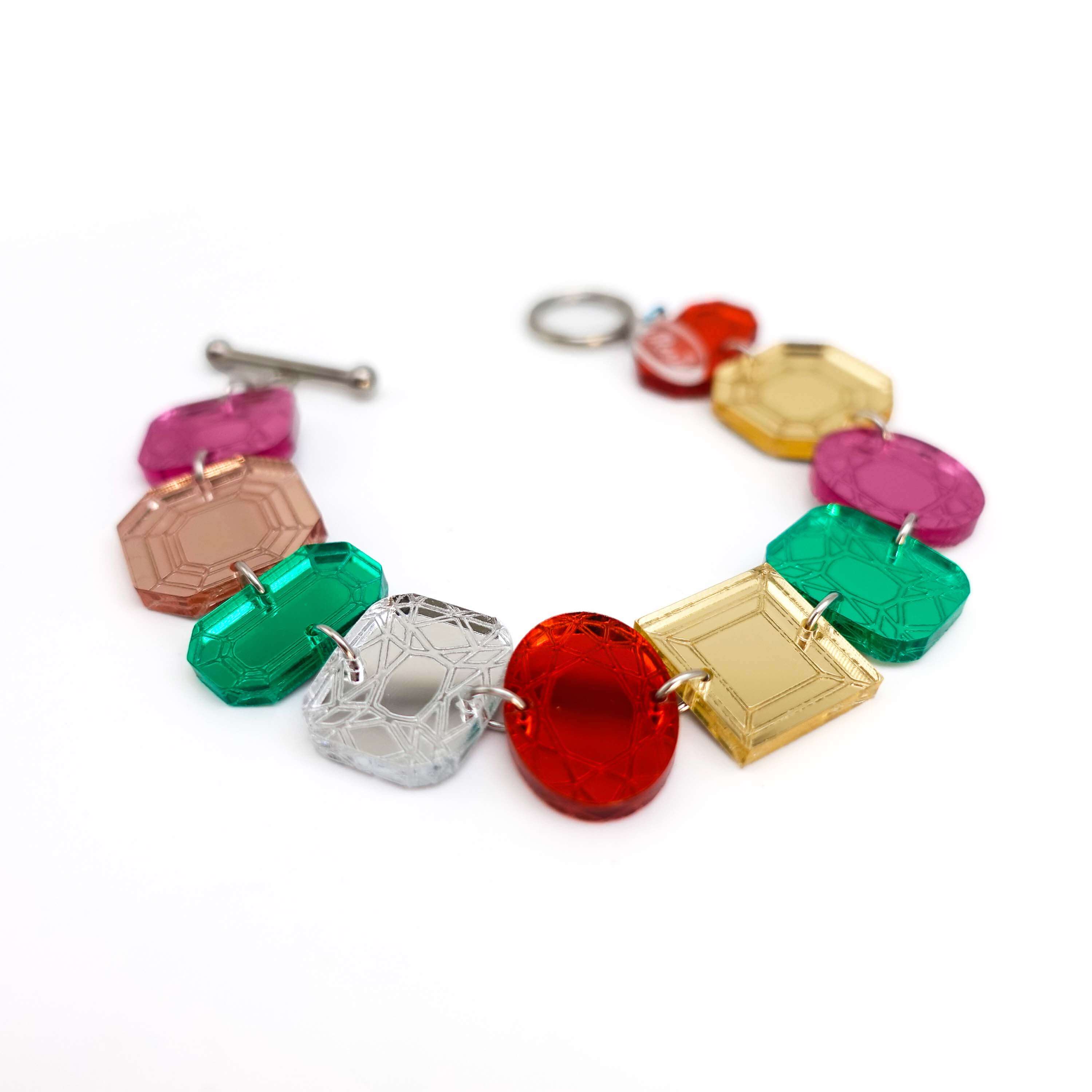 Jewel bracelet with stainless steel toggle clasp shown lying on a white surface. 