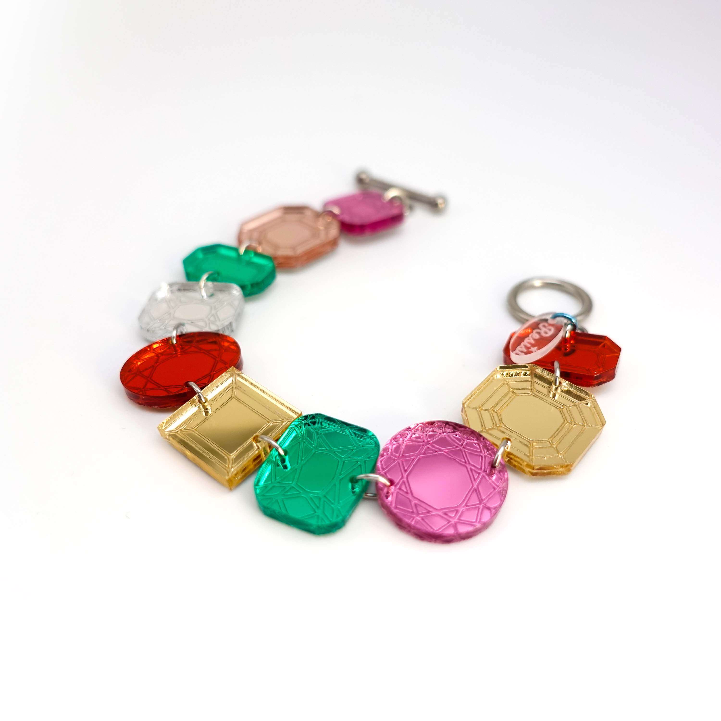 Jewel bracelet with stainless steel toggle clasp shown lying on a white surface. 