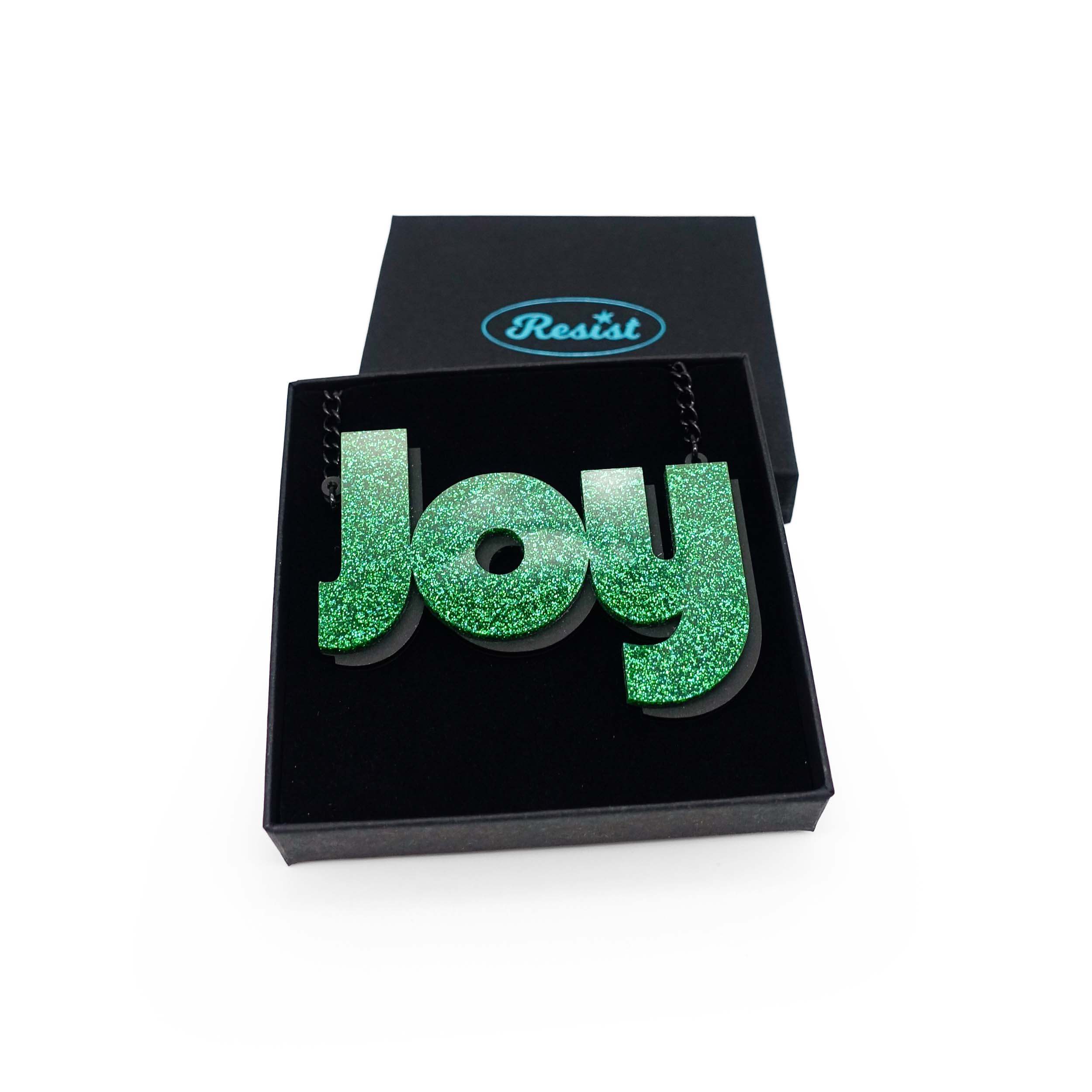 Joy statement necklace in green glitter, shown in a Wear and Resist gift box. 