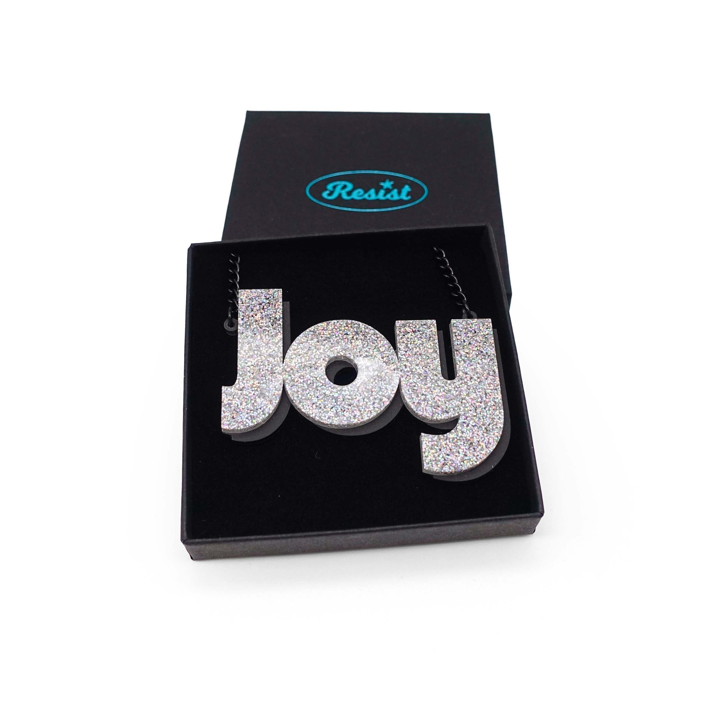 Joy statement necklace in silver glitter, shown in a Wear and Resist gift box. 