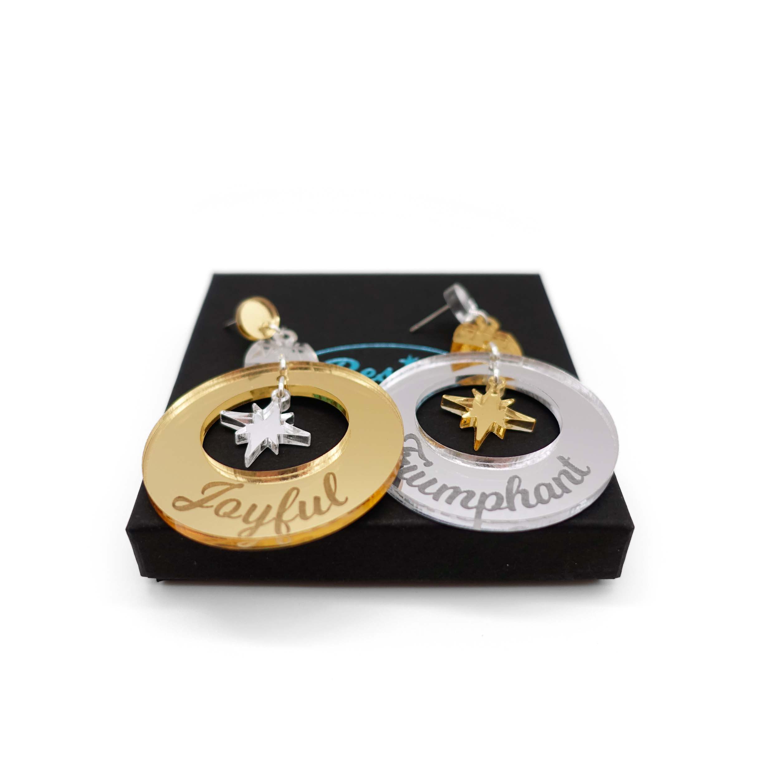 Joyful and Triumphant Christmas Bauble earrings in gold and silver, resting on a Wear and Resist gift box. 