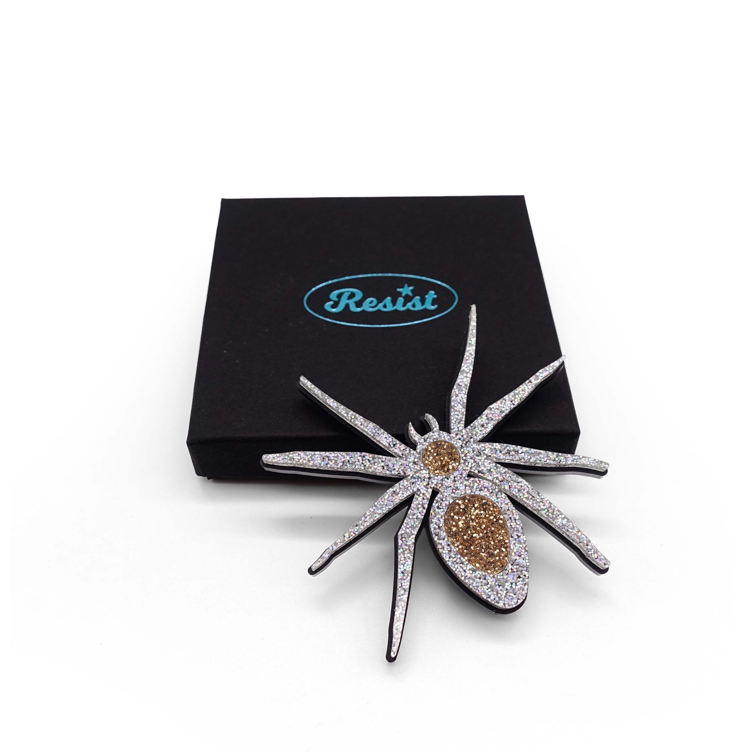 All Hail Lady Hail Spider brooch, designed by Sarah Day in 2019 in honour of Lady Hale's infamous spider brooch. Shown here crawling onto a Wear and Resist gift box. 