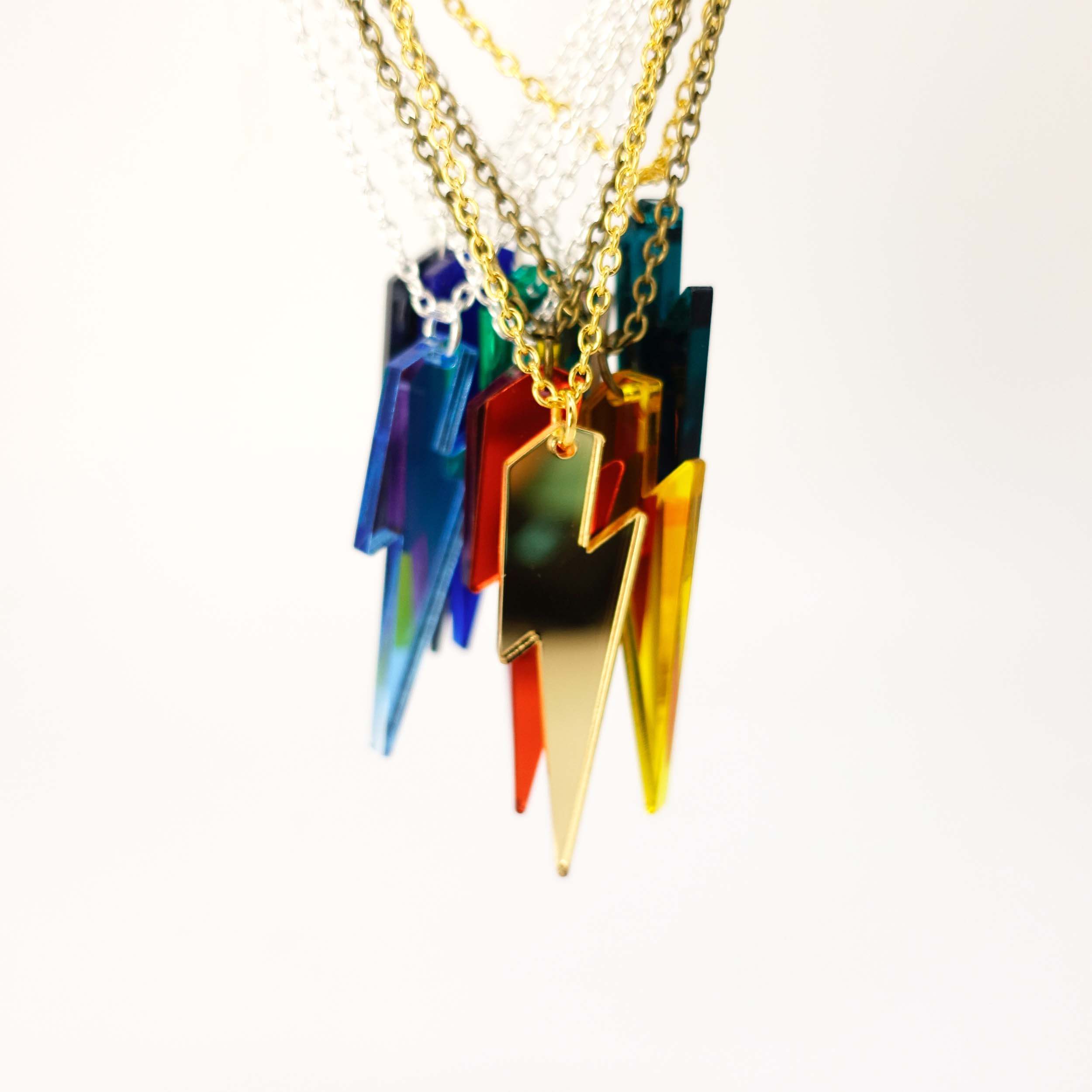 A group of Lightning Bolt necklaces in all the different mirror colours shown hanging against a white background. 