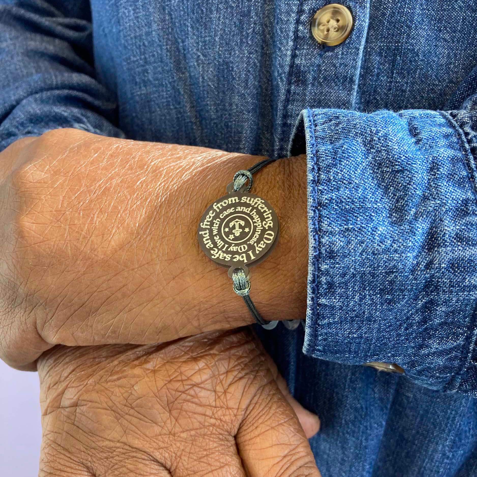 A member of Women for Refugee Women wears a May I Be Safe bracelet in shale from The Courage Collection.