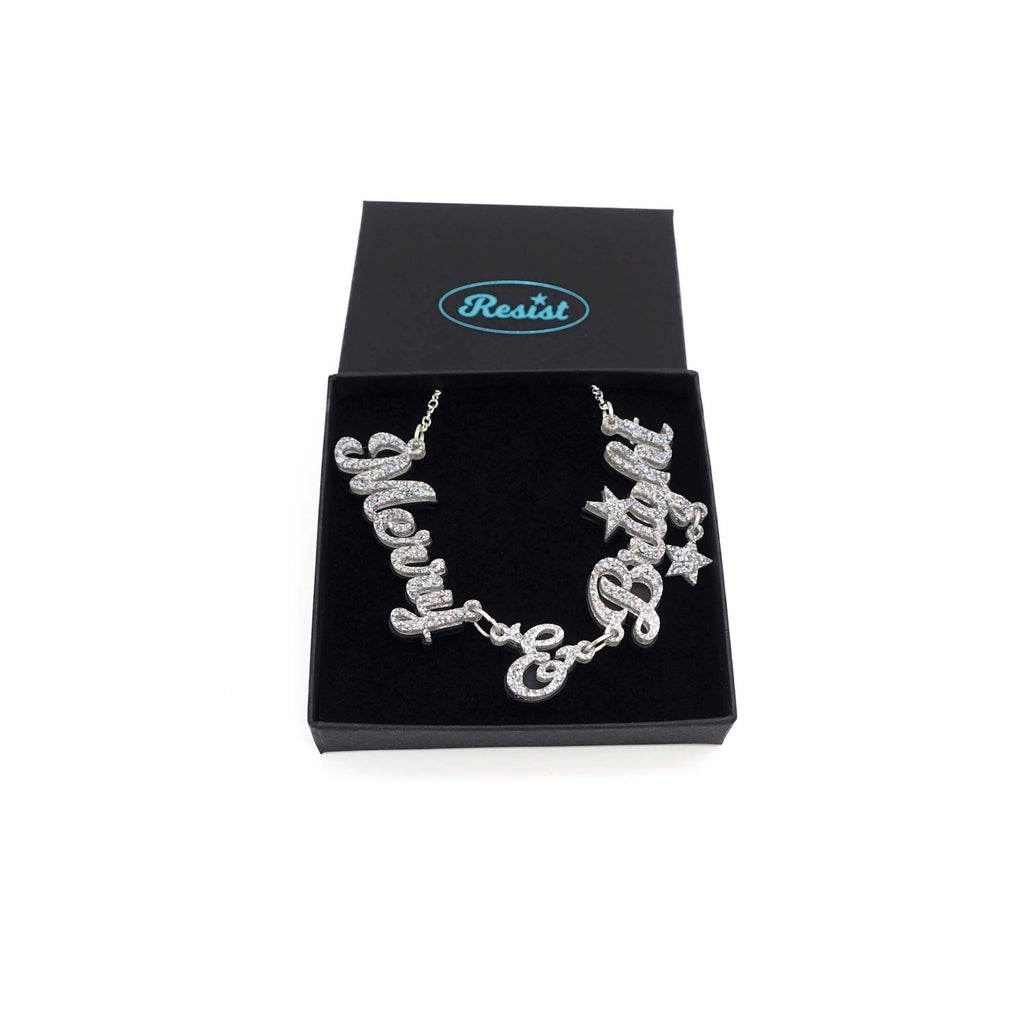 Silver glitter Merry & Bright necklace shown in a Wear and Resist gift box. 