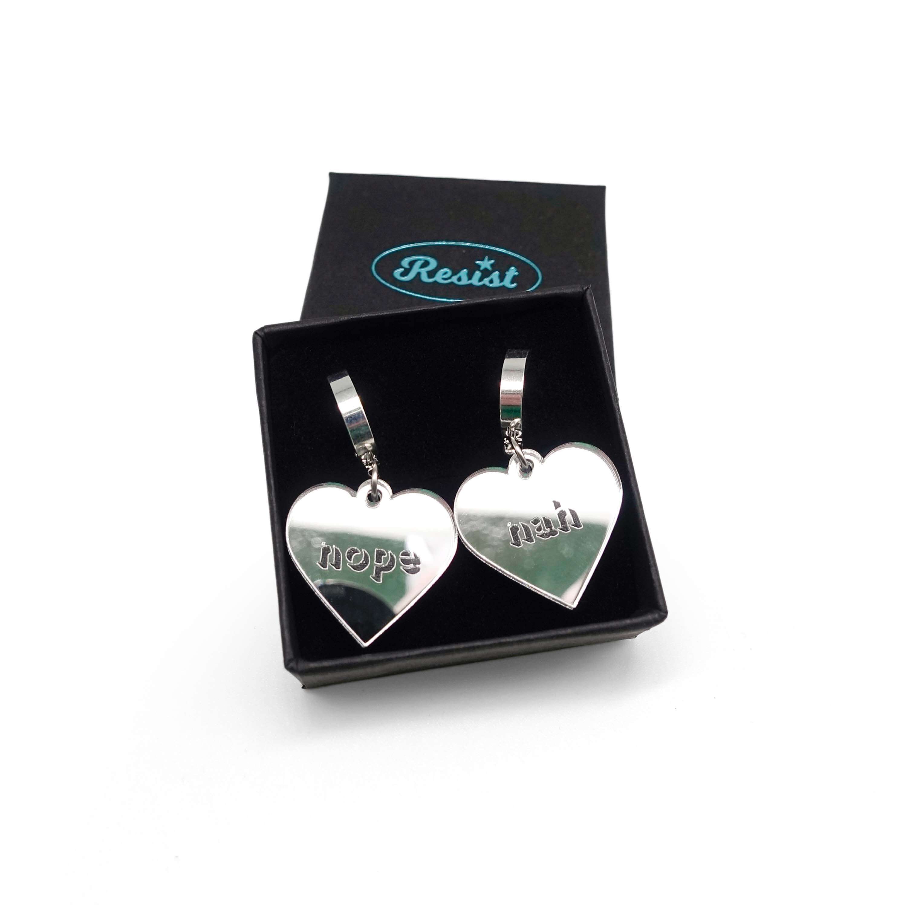 Nah Nope heart shaped huggie hoop earrings in silver mirror shown in a small Wear and Resist gift box. 