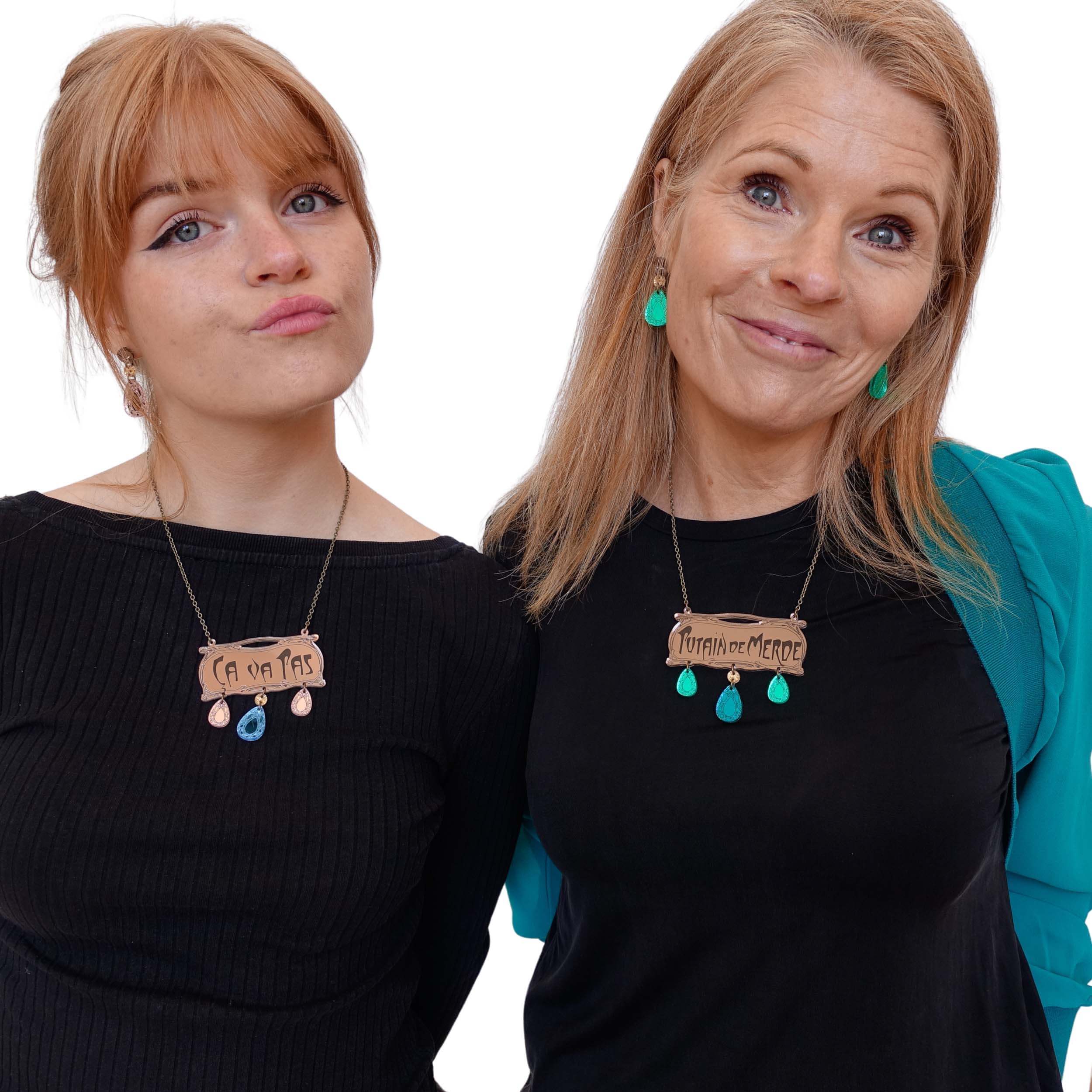 Eliza wearing French CA VA PAS necklace and matching rose gold French drop earrings, while Sarah wears the swearier P*TAINE DE M*RDE necklace, and matching electric green French drop earrings from the Austerity Jewels Belle Epoque Paris-inspired collection.  
