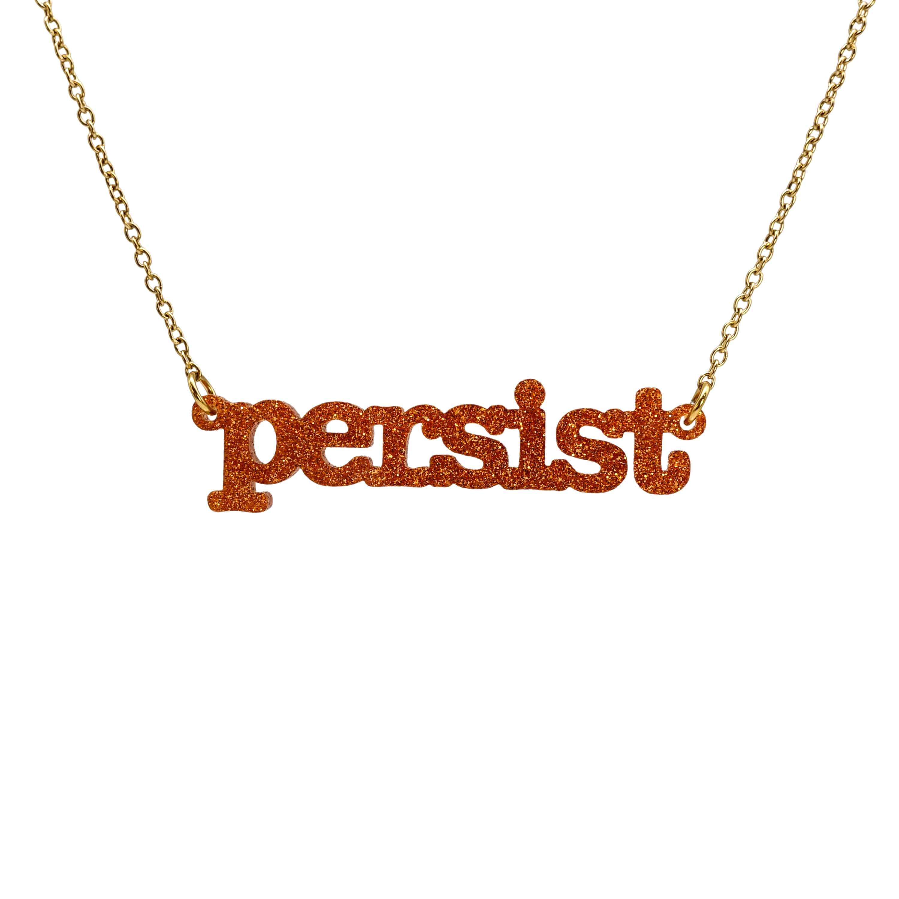 Typewriter Resist necklace in flame glitter shown hanging on a gold plated stainless steel chain against a white background. 