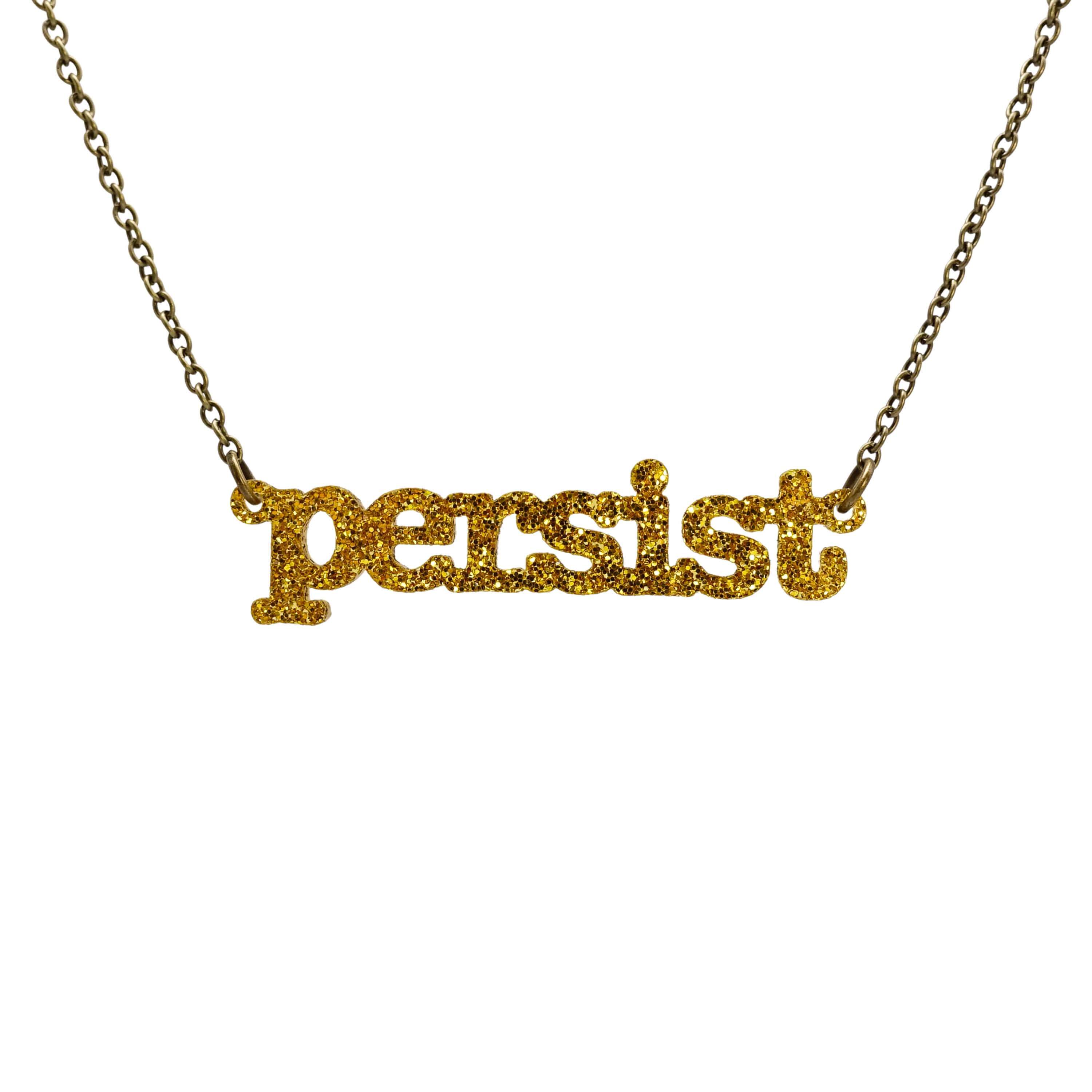 Typewriter Resist necklace in ultra gold glitter shown hanging on an antique gold chain against a white background. 