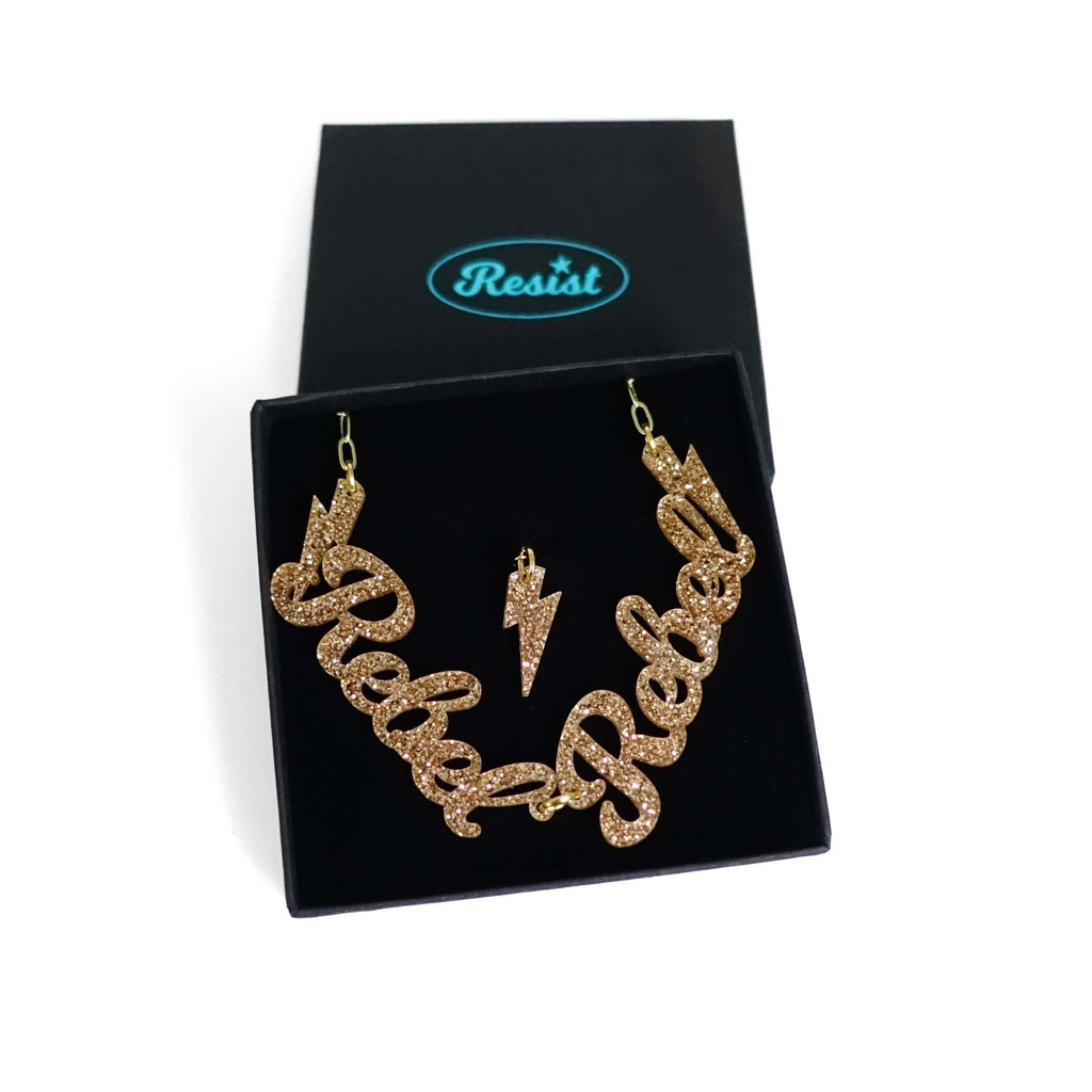 Gold glitter Rebel Rebel necklace shown in a Wear and Resist gift box. 