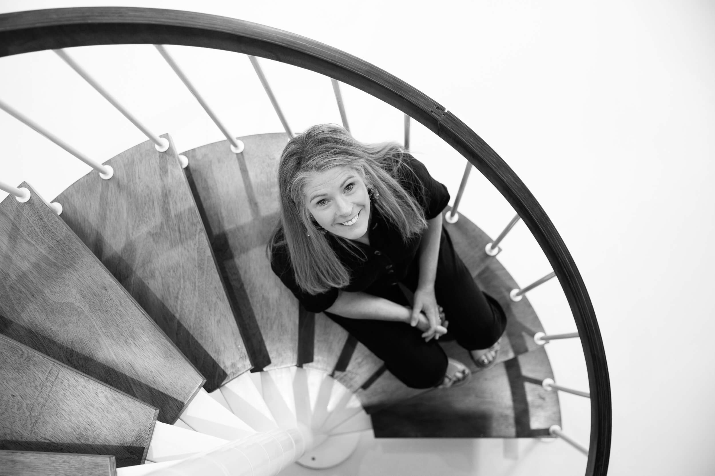Sarah Day, the founder of Wear and Resist, sitting on the spiral stairs in her Oxfordshire studio. 