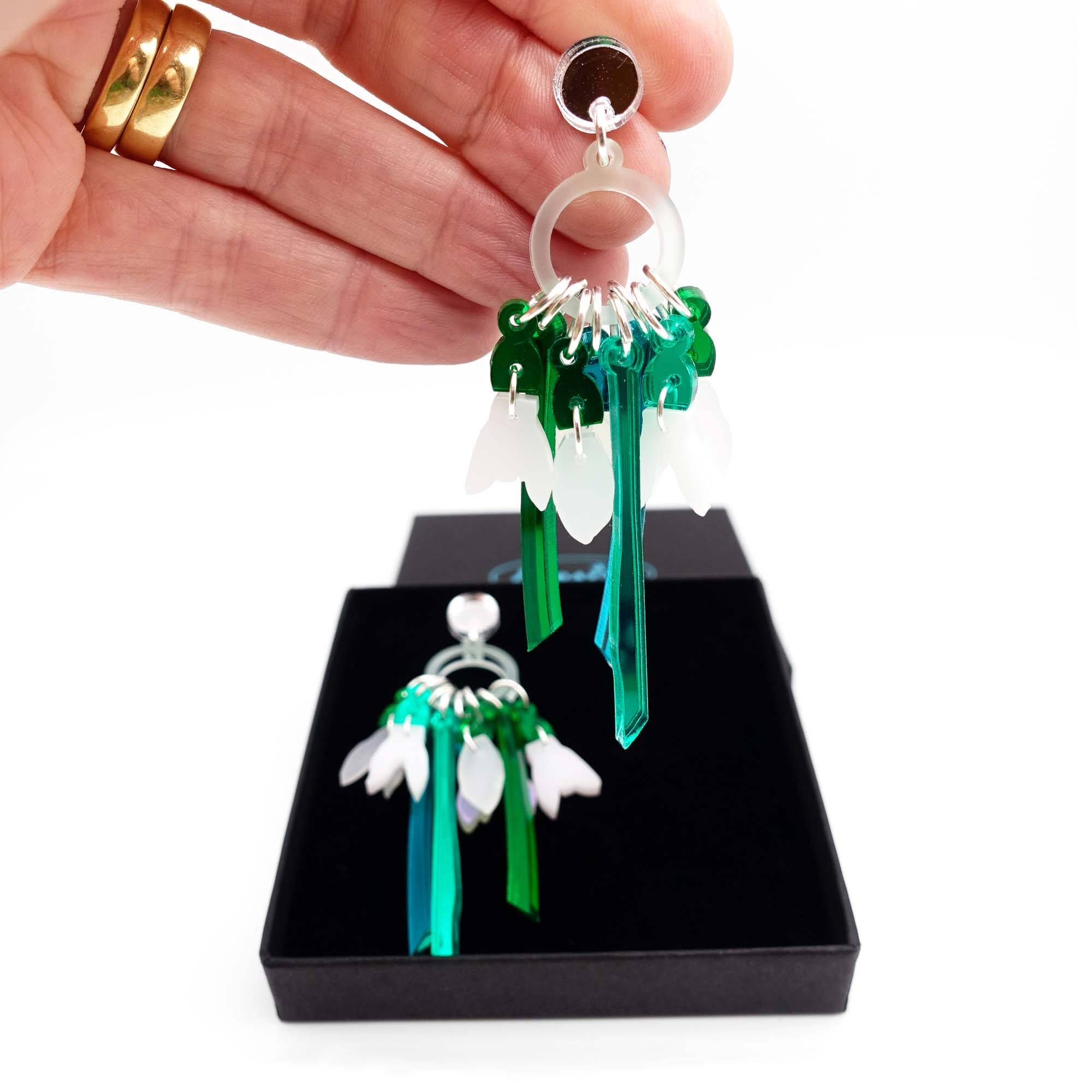 Snowdrop earrings designed by Sarah Day for Wear and Resist shown being lifted from a Wear and Resist gift box. 