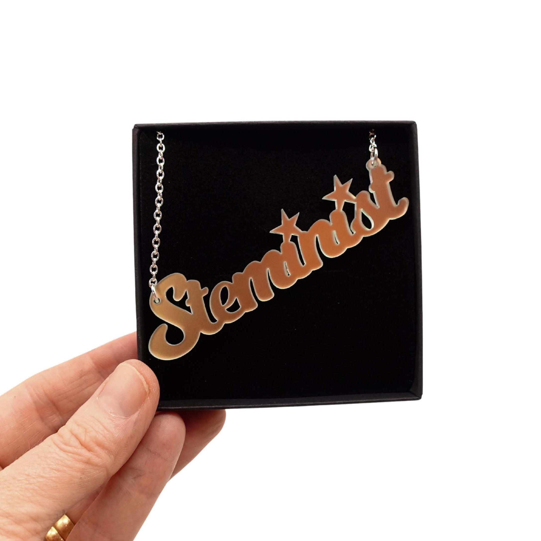 Steminist necklace for women working in STEM in matte iridescent shown held up in a Wear and Resist gift box. 