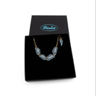 This too shall pass bracelet with words etched in glow-in-the-dark pigment on small clouds on a gold-plated stainless steel chain, show in a Wear and Resist gift box. 