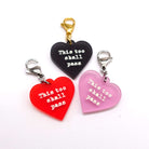 Heart charms etched and hand-painted with the words This too shall pass in glow in the dark pigment. 