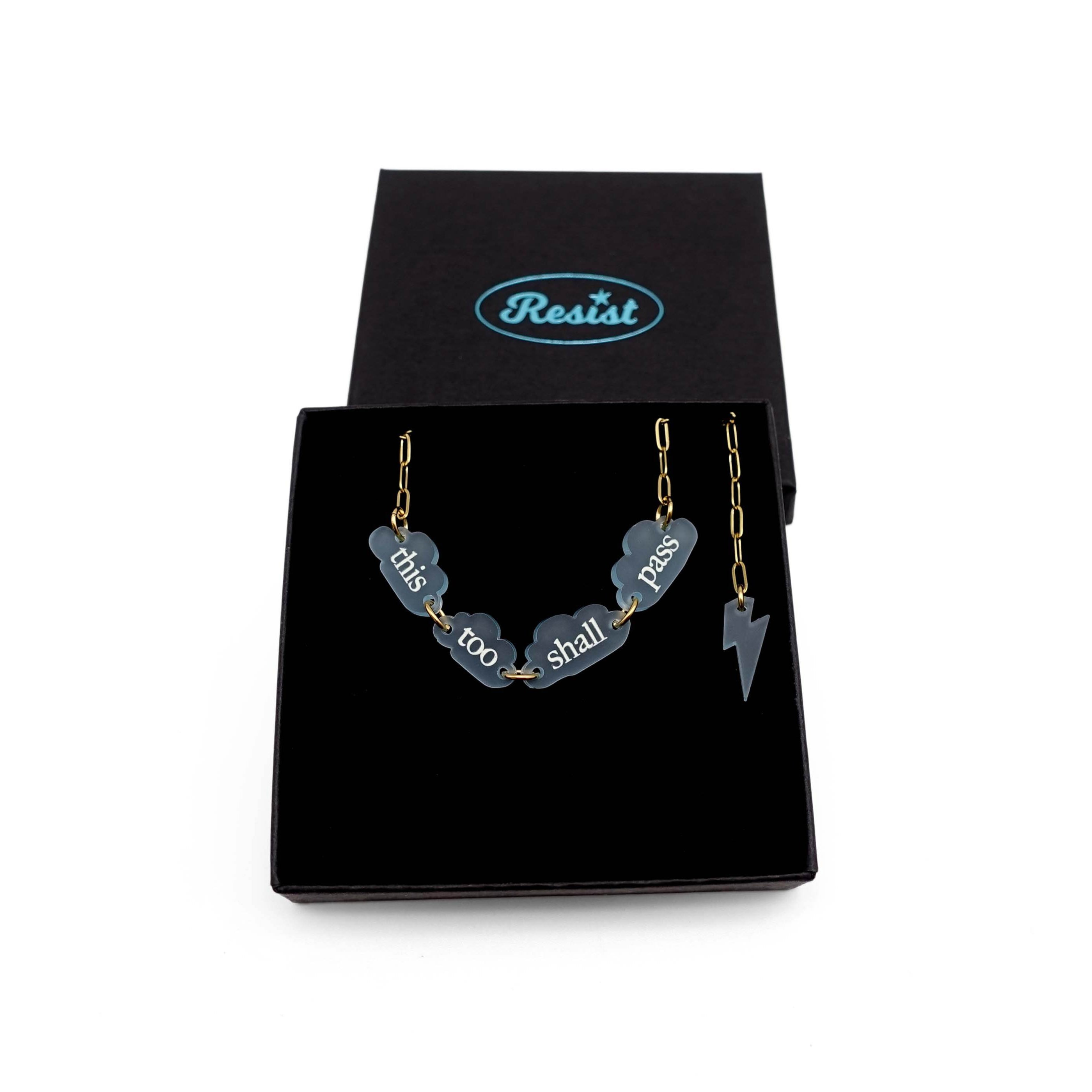This Too Shall Pass floating clouds necklace shown on an 18K gold ion-plated stainless steel chain in a Wear and Resist gift box.