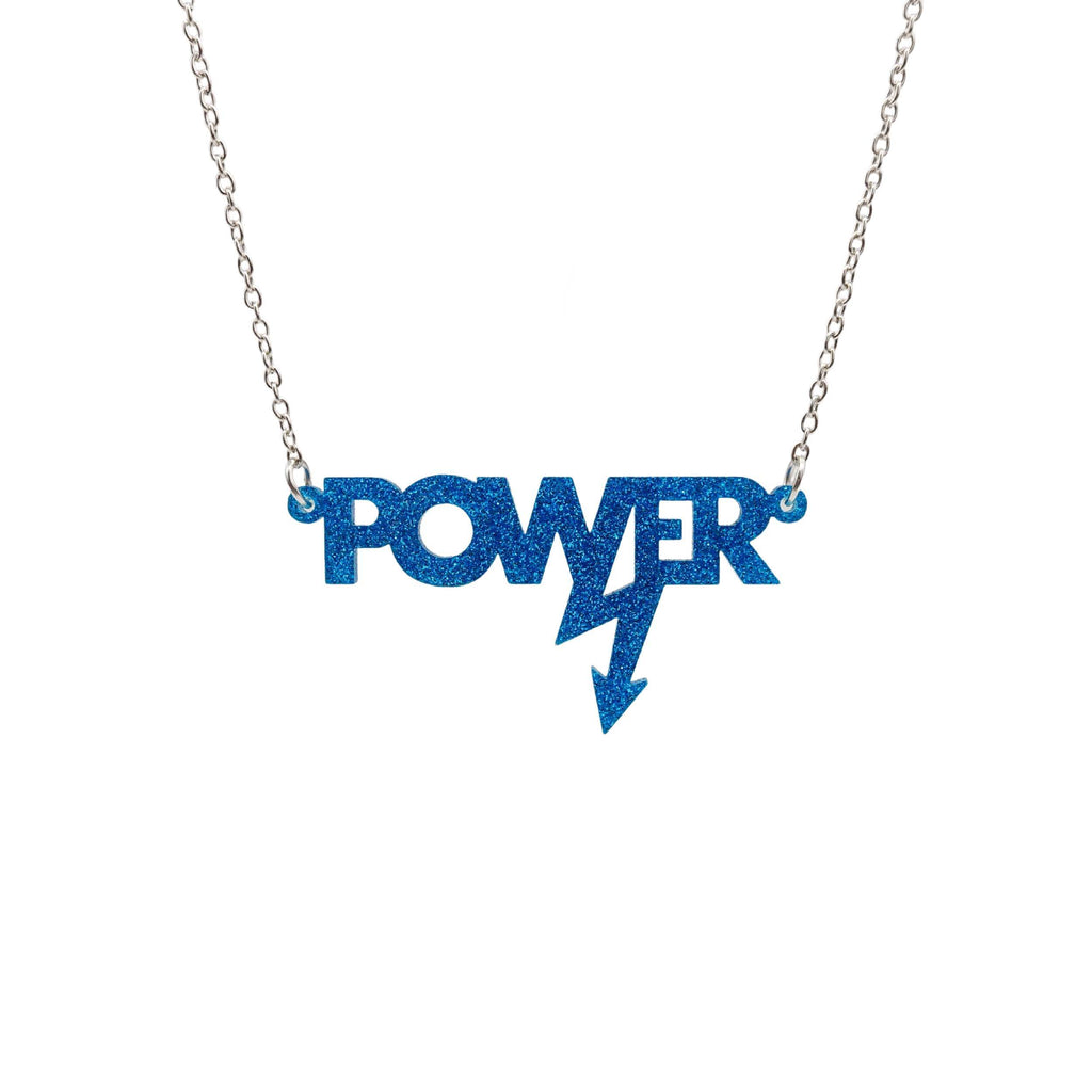Mini power necklace in blue glitter shown hanging on a silver chain against a white background. Designed in collaboration with Mary Beard for her book Women and Power. 