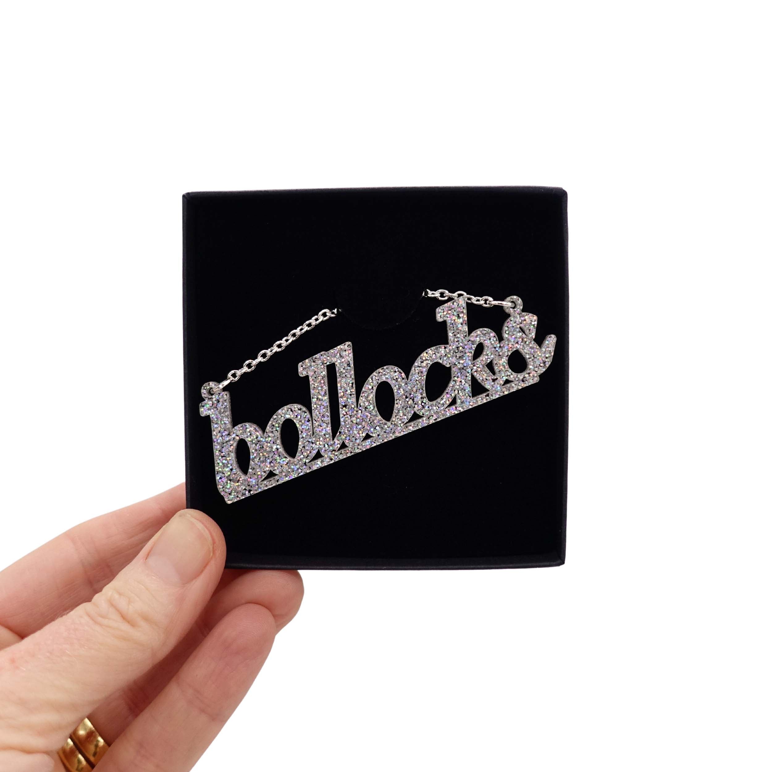 Bollocks necklace in silver glitter shown in a Wear and Resist gift box. 