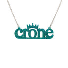 Bright teal glitter CRONE necklace shown hanging on a stainless steel chain in front of a white background. 