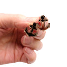 Small bronze anchor earrings shown held in my hand. 