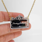 A very sweary florid necklace shown etched in silver mirror hanging on a gold plated chain with my hand behind for scale. 