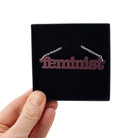 Cassis Feminist necklace shown in a Wear and Resist gift box. 