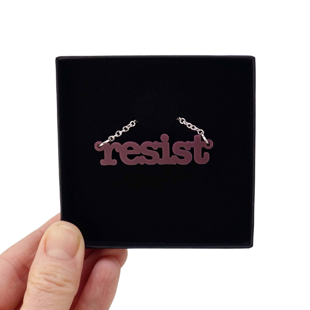 Cassis Resist necklace in typewriter font shown in a Wear and Resist gift box. 